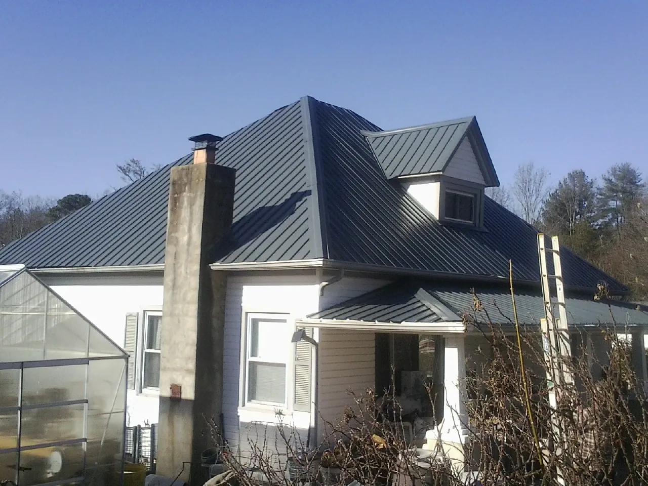 Dark blue standing seam metal roof on a white farmhouse with dormer — Slate & Tile Roof Repair by Roofing Brothers in Agoura Hills