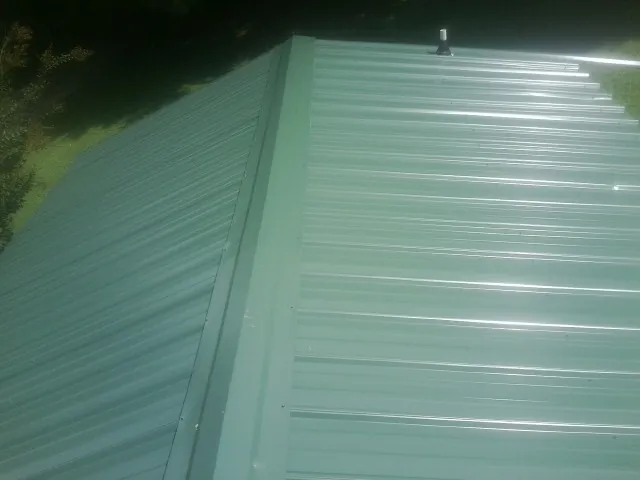 New green metal panels meeting at the ridge of a roof — Flat Roof Repair work by our crew in Agoura Hills