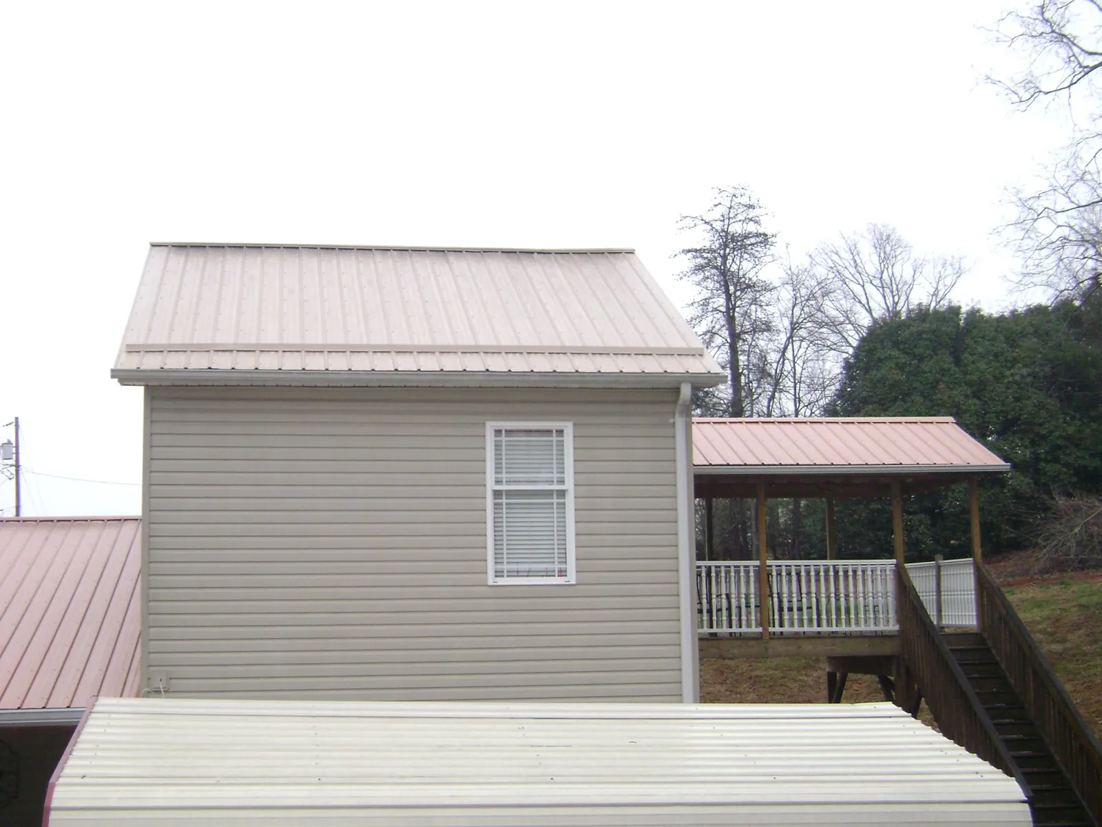 Tan metal roofs on a two story addition and attached porch, from a Roof Replacement job in Agoura Hills