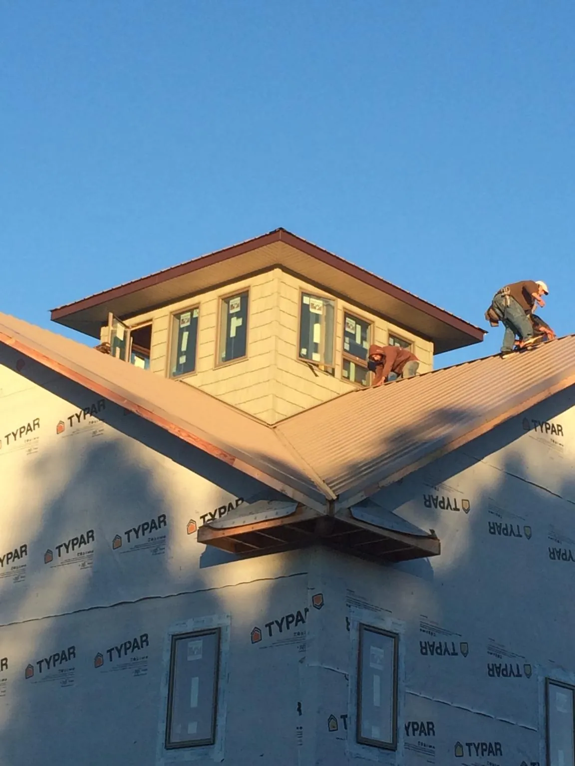 Roofers working around a rooftop cupola on a new metal roof at sunset — Roof Waterproofing in Agoura Hills by Roofing Brothers
